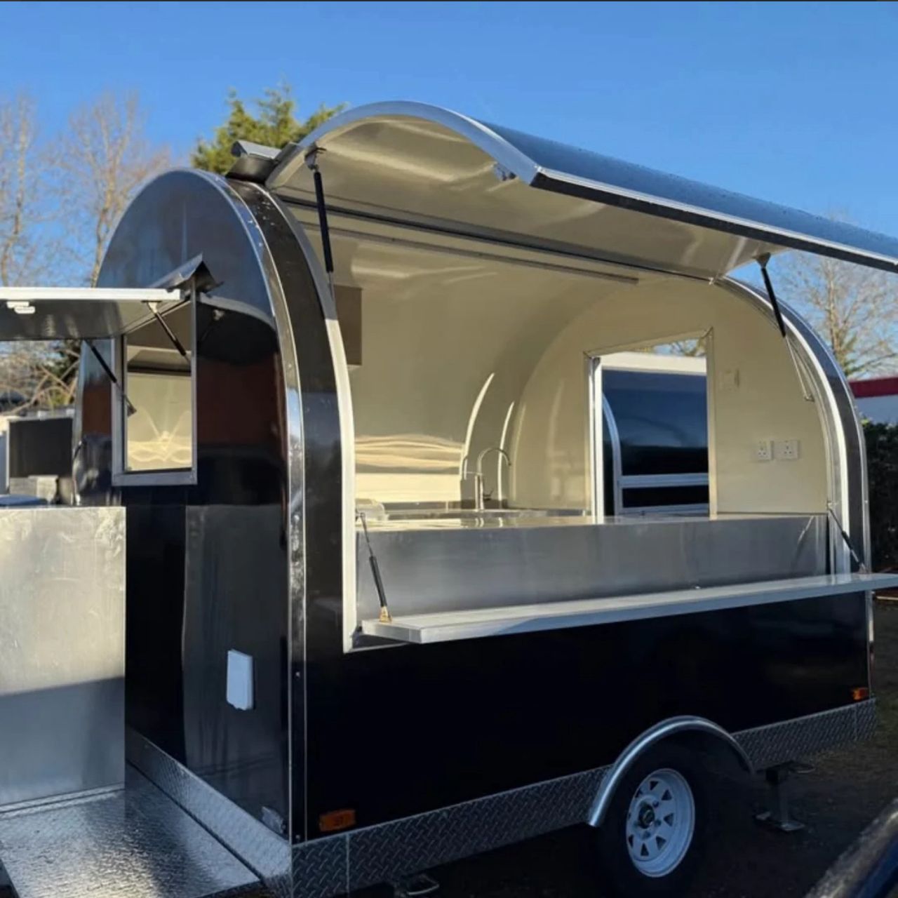 IMG-20260519-WA0013 - Mobile food concession trailer with a curved aluminum shell, open service window, and diamond-plate deck outdoors.